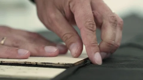 A man aligns the fabric on the patterns. Close-up Stock Footage 128461384