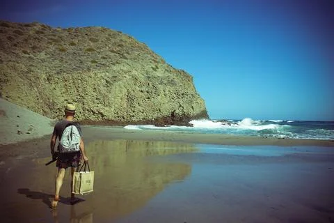 A man alone with a backpack walking on a beach Stock Photos