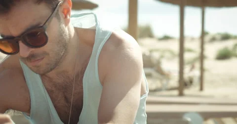 Man alone on the beach placing items on deckchair Stock Footage 205026978