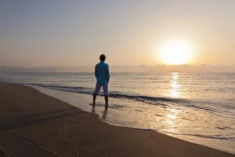Man alone on beach watching the sunset Stock Photos