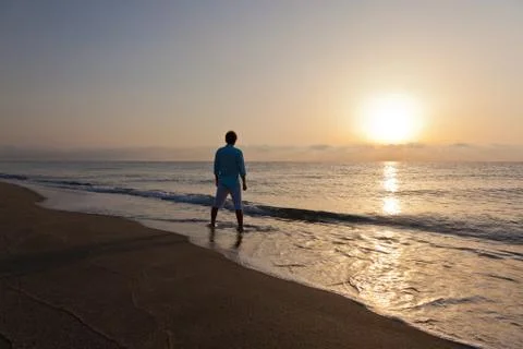 Man alone on beach watching the sunset Stock Photos
