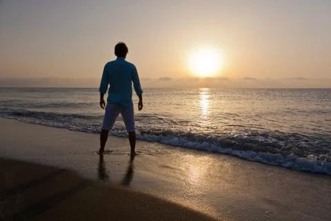 Man alone on beach watching the sunset Stock Photos