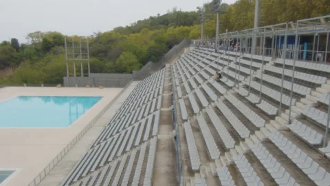 A man alone on the bleachers of an empty municipal pool, in Barcelona, Spain Stock Footage 221122656