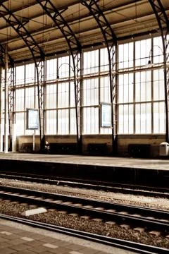 A man alone at the empty train station with stained big window behind in Harl Stock Photos