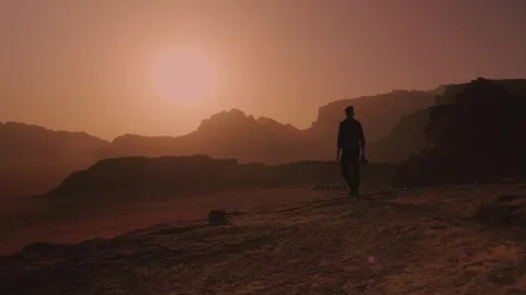 Man alone walking towards a red sunset in Wadi Rum, Jordan desert Stock Footage 308327593