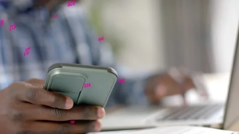 Man alternating tapping smartphone and typing laptop for tech work, pink Stock Footage 333689706