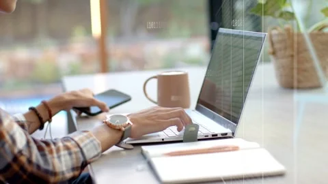 Man alternating typing on laptop, using phone at window desk, causing tech UI Stock Footage 335761658