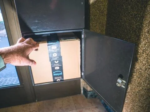 Man with Amazon cardboard box parcel in mailbox Stockfoto's