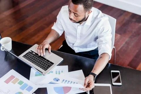 Man analysing data and using laptop at desk in home office Stock Photos