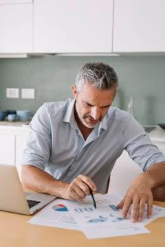 Man analysing data and using laptop in home office Stock Photos