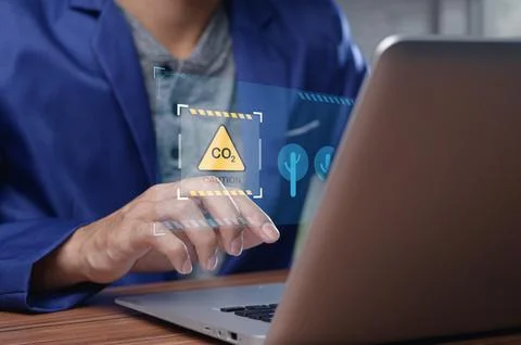 Man Analyzing Carbon Dioxide Levels on Laptop Screen in Office Stock Photos