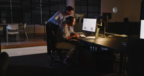 Man analyzing data on computer while colleague points at screen, at office Stock Footage 315966782