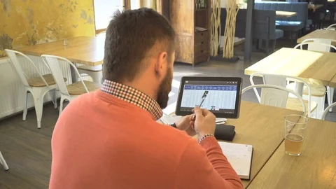 Man analyzing data on tablet and writing notes, in cafe, close behind shot Vídeos de archivo 73293423