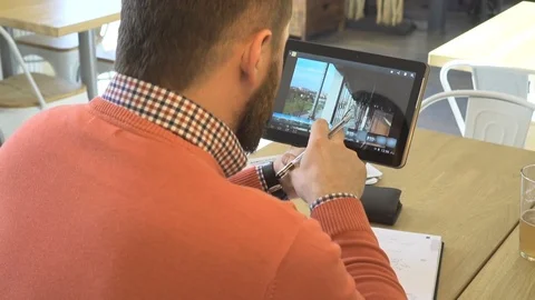Man analyzing project, photos on tablet, make notes, in cafe, close behind shot Vídeo Stock 73293566