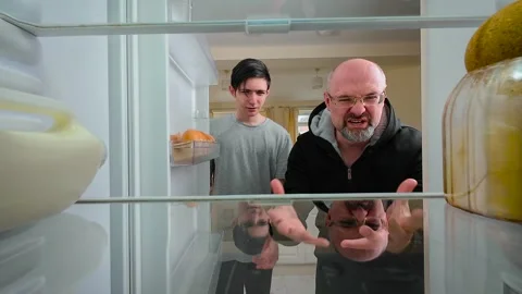Man and boy arguing in front of empty fridge, disappointed by lack of food, view Stock Footage 308311070