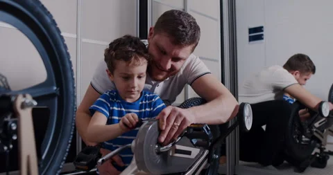 A man and a boy bond over building a bike, showcasing teamwork Stock Footage 307311567