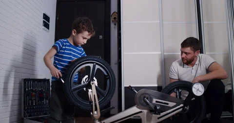 A man and boy bond while working together to fix a bike tire Video stock 307306739