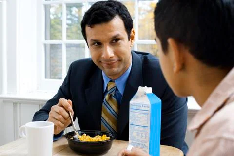 Man and boy at breakfast table smiling Foto stock