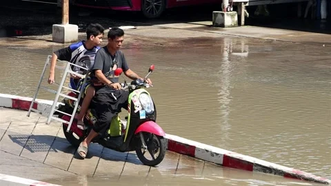 A man and a boy carry a load on a motorbike through a flooded street Stock Footage 219486039