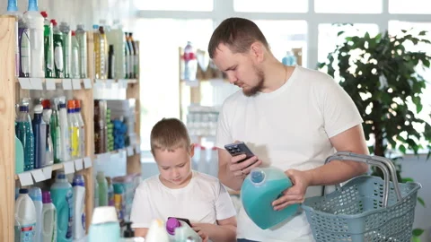 Man and boy scanning qr code for detergent Stock Footage 309524069