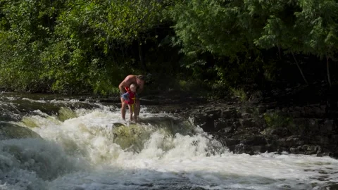A man and child edge at of smallscale waterfall Stock Footage 166620141
