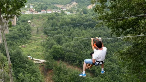 Man and child having fun moving on zip line above big canyon Stock Footage 104825973
