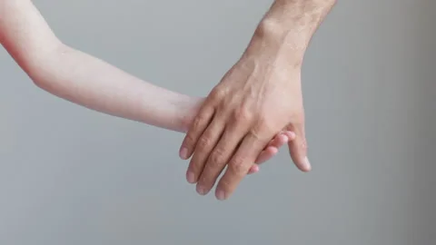 Man and child join hands and hold against the background of a white wall Stock Footage 170546306