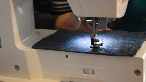 Man and child using a sewing machine with a blue garment, for repair work, .. Stock Footage 258348553