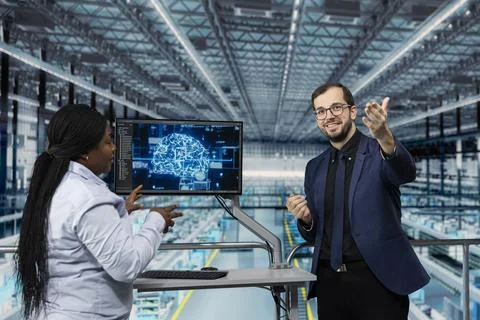 Man and colleague using artificial intelligence to optimize microchip factory Stock Photos