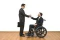 The man and a disabled in wheelchair handshake on the white wall background Photo