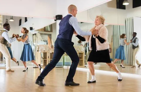 Man and elderly woman performing jazz dance in dancing room Stock Photos