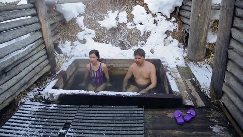 A man and a girl take a bath of hot natural mineral springs in the open in winte Video stock 73768942