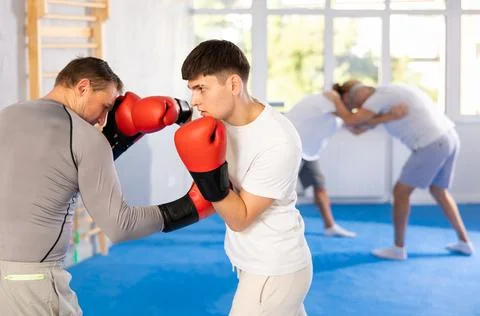 Man and guy in boxing gloves punch deliver blow each other during training Stock Photos