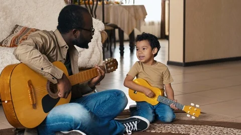 Man and his son playing guitars and singing song Stock Footage 100690249