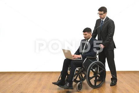 The man and an invalid work with a laptop on the white wall background Stock Photos