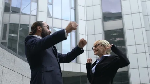 Man and lady in suits making winner gesture and smiling, successful business 動画素材 119036497