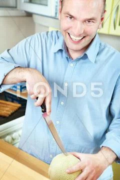Man and melon in kitchen Stock Photos