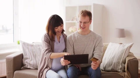 Man and pregnant wife shopping online at home Stock Footage