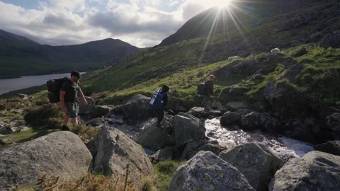 Man and sons walking over gorgeous Welsh countryside with stream and mountains Stockbeeldmateriaal 155834264