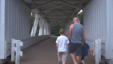Man and Sons Walking Under a Covered Bridge Stock Footage 91592603