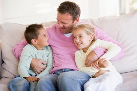 Man and two children sitting in living room smiling Stock Photos
