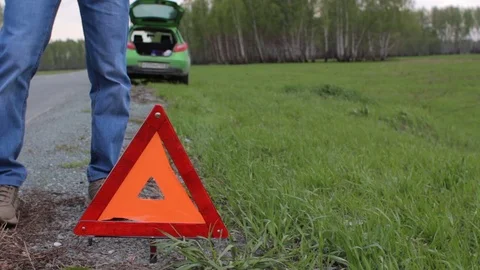 Man and warning triangle on the road. Car failure in the forest Stock Footage 75919836