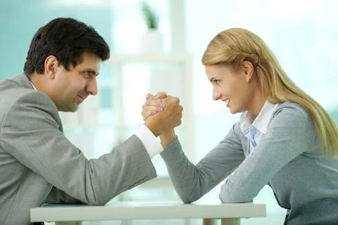 Man and woman in arm wrestling gesture on working table during meeting Stock Photos