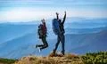 The man and a woman with backpacks jumping on the mountain Photo