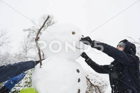 Man And Woman Building Snowman Together
