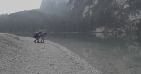 Man and woman couple playing throw rocks into Braies lake. Group of friends Stock Footage