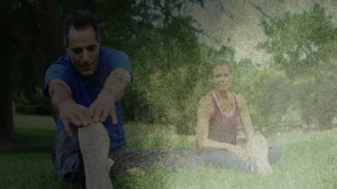 Man and woman doing hamstring stretch in park, fading light streak revealing Stock Footage 333485452