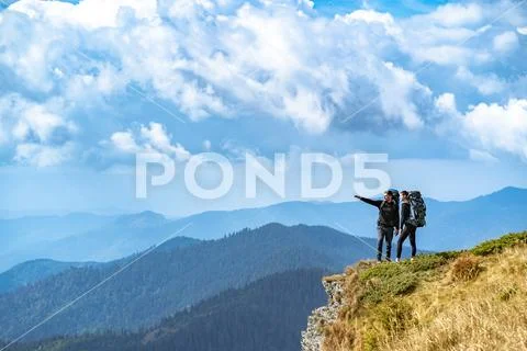 The man and a woman gesturing on the cliff with a beautiful view Stock Photos