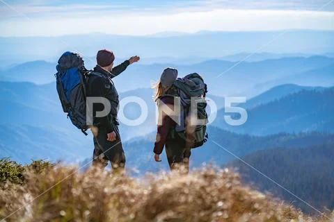 The man and a woman gesturing on the cliff with a beautiful view Stock Photos