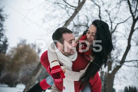 Man and woman having fun in the snow-covered park Stock Photos